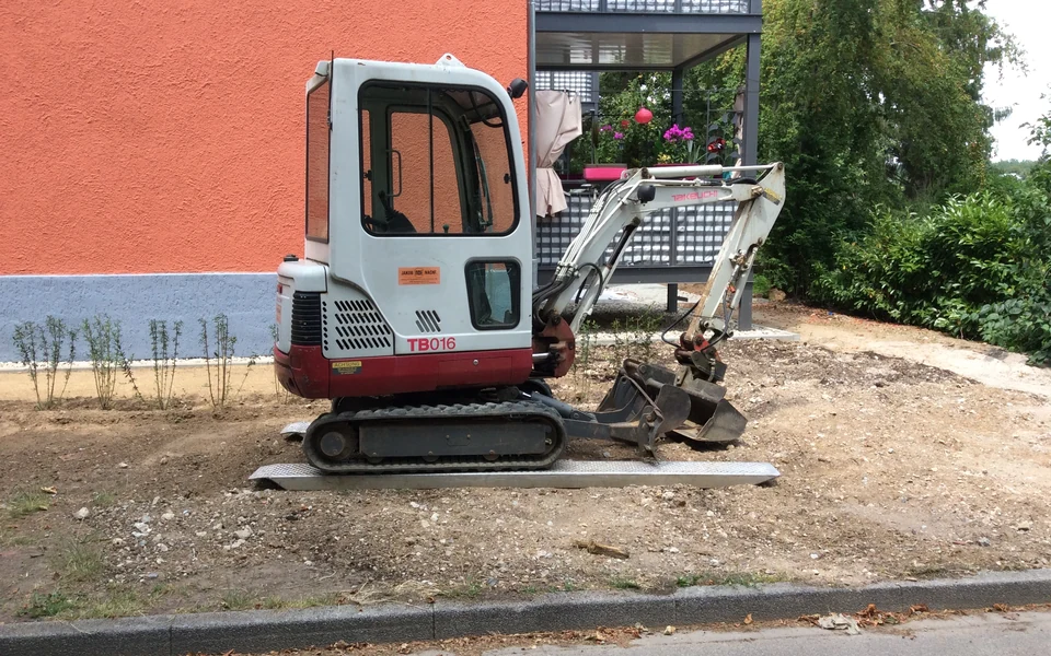 A compact tracked mini digger with a cab and bucket.