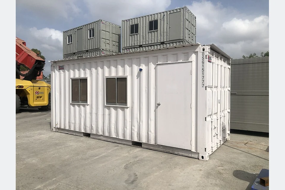 A shipping container converted into an office, with door and windows.